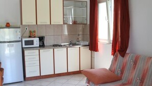A compact kitchen with a microwave, coffee maker, and sink. There is a sofa with a cushion and a window with curtains. - Apartment in Ražanj with Seaview, Balcony, Air condition, WIFI (5150-4) (Ražanj)