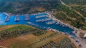 An aerial view of a marina with numerous boats docked, surrounded by terraced agricultural fields and hilly terrain. - Apartment in Primošten with Seaview, Terrace, Air condition, WIFI (5155-1) (Primošten)