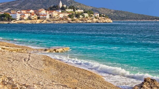 A coastal town with buildings on a hillside, a rocky beach, and clear blue waters. - Apartment in Primošten with Seaview, Terrace, Air condition, WIFI (5155-1) (Primošten)