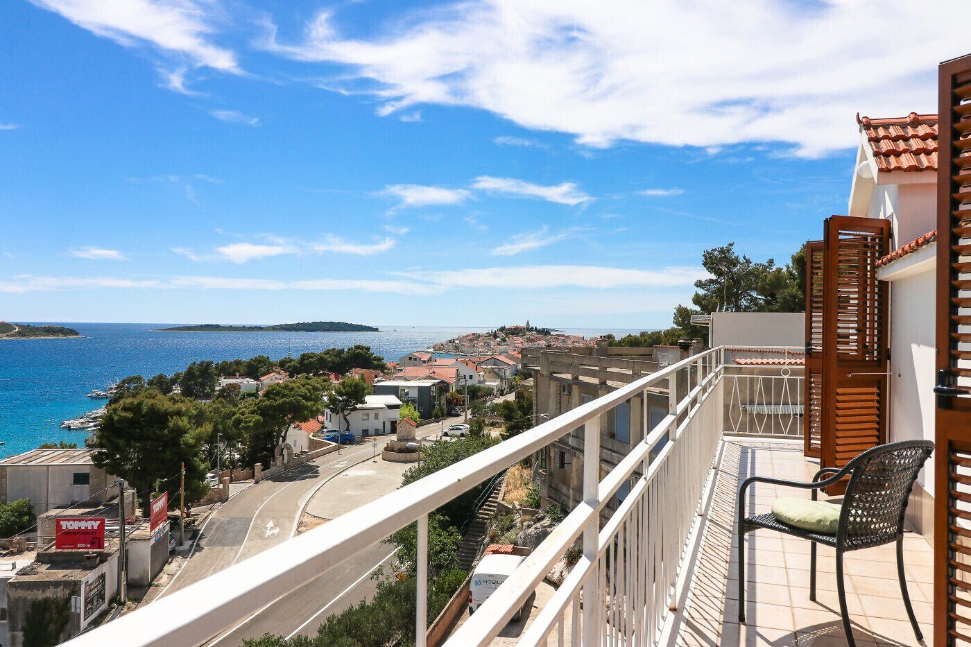 Un balcón con vista al mar, una calle y edificios.