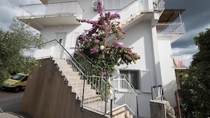 A two-story building with a staircase leading to the upper floor, surrounded by greenery and a parked car. - Apartment in Stupin Čeline with Seaview, Balcony, Air condition, WIFI (5149-1) (Podglavica)