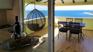 A dining area with a view of the ocean, a hanging chair, and a table with chairs.