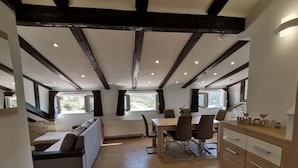 A modern kitchen with a dining area, wooden beams on the ceiling, and a view of the outdoors.