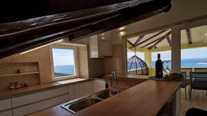 A modern kitchen with a wooden countertop, a built-in sink, and a view of the sea through large windows.