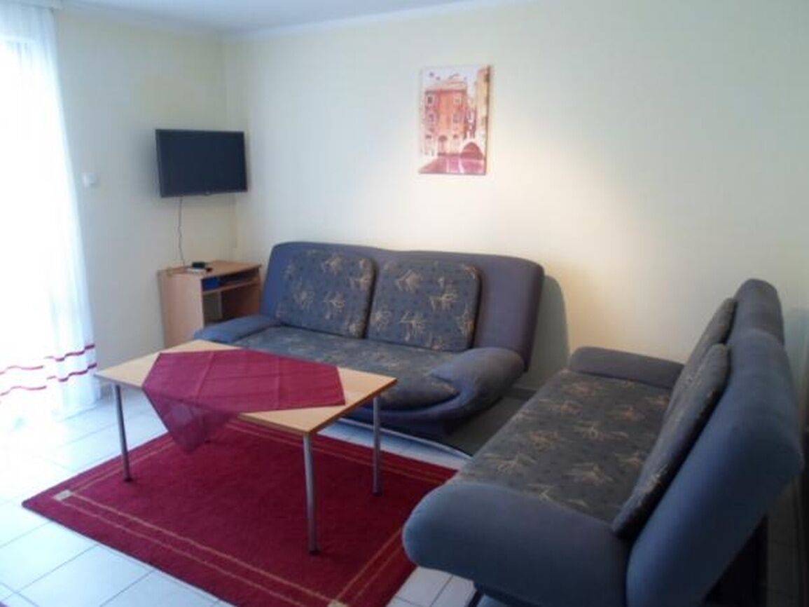 Ein Wohnzimmer mit einer Couch, einem kleinen Tisch und einem Fernseher an der Wand.