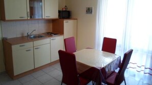 A compact kitchen with a dining table and chairs, a sink, and cabinets. - Apartment in Rogoznica with Seaview, Balcony, Air condition, WIFI (5153-2) (Rogoznica)
