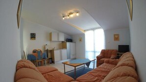 A compact living space with a sofa set, a dining area, and a kitchen.