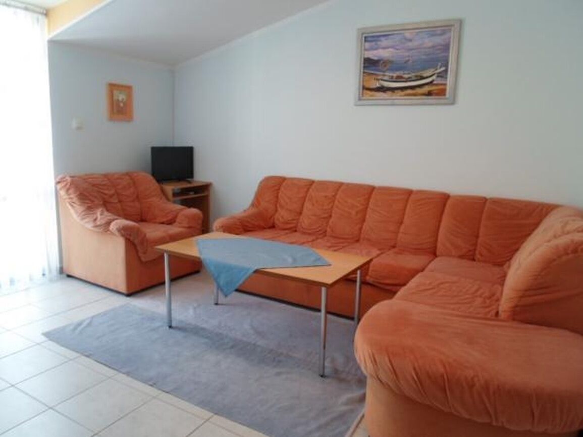En stue med sofa, lænestol, lille bord og fjernsyn.