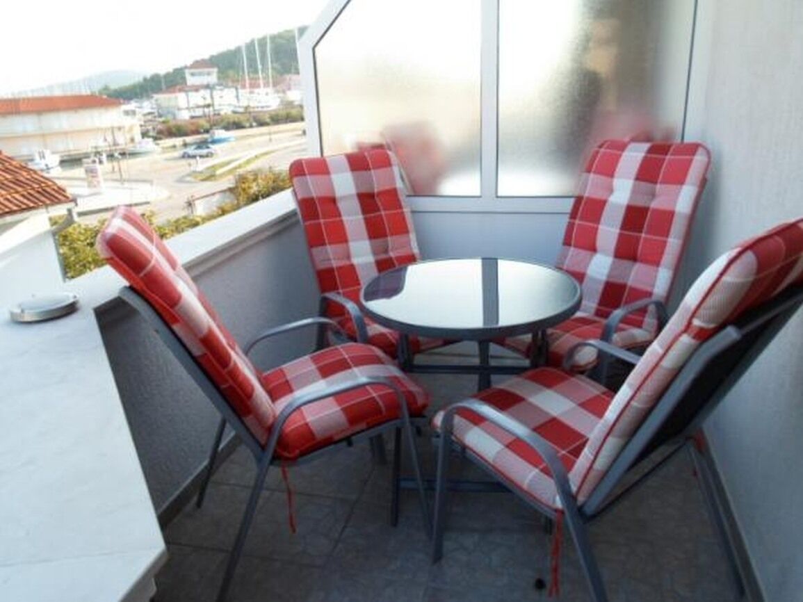 A balcony with a round table and four red and white checkered chairs.