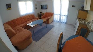 A living room with a sofa, a small table, and a TV. There is a balcony with a view. - Apartment in Rogoznica with Seaview, Balcony, Air condition, WIFI (5153-3) (Rogoznica)
