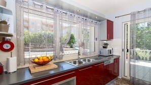 A modern kitchen with red cabinets, a stainless steel sink, and a window with sheer curtains. - Apartment in Okrug Gornji with Terrace, Air condition, WIFI, Washing machine (5157-1) (Okrug Gornji)