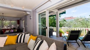 A modern living room with a grey sofa, yellow and white cushions, and a dining area with a kitchen in the background. - Apartment in Okrug Gornji with Terrace, Air condition, WIFI, Washing machine (5157-1) (Okrug Gornji)