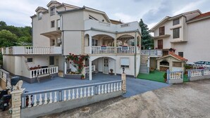 A multi-story residential building with balconies, a covered patio, and a small garden area.