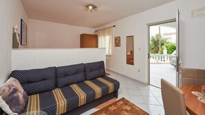 A living room with a sofa, a dining table, and a view of the outside.