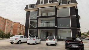 Een modern gebouw met een zwart-wit gevel, grote ramen en een parkeerplaats met meerdere auto's.