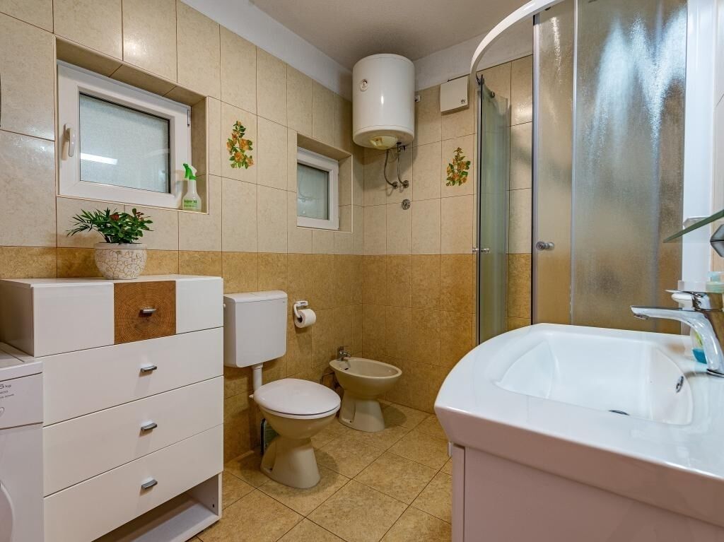 A bathroom with a toilet, bidet, sink, and a shower with a glass door.