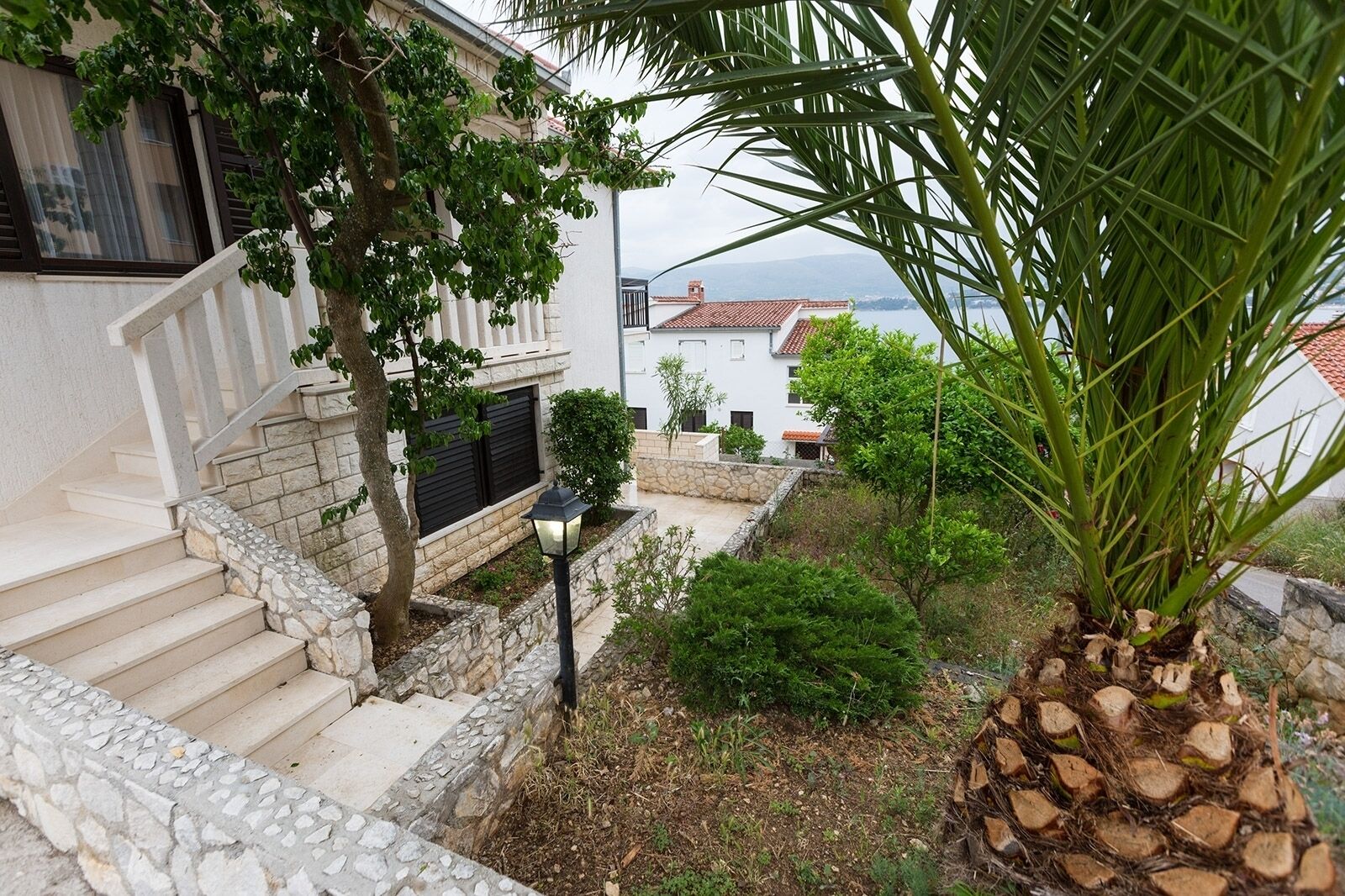 Un escalier menant à un bâtiment blanc, avec des marches en pierre et un palmier au premier plan.