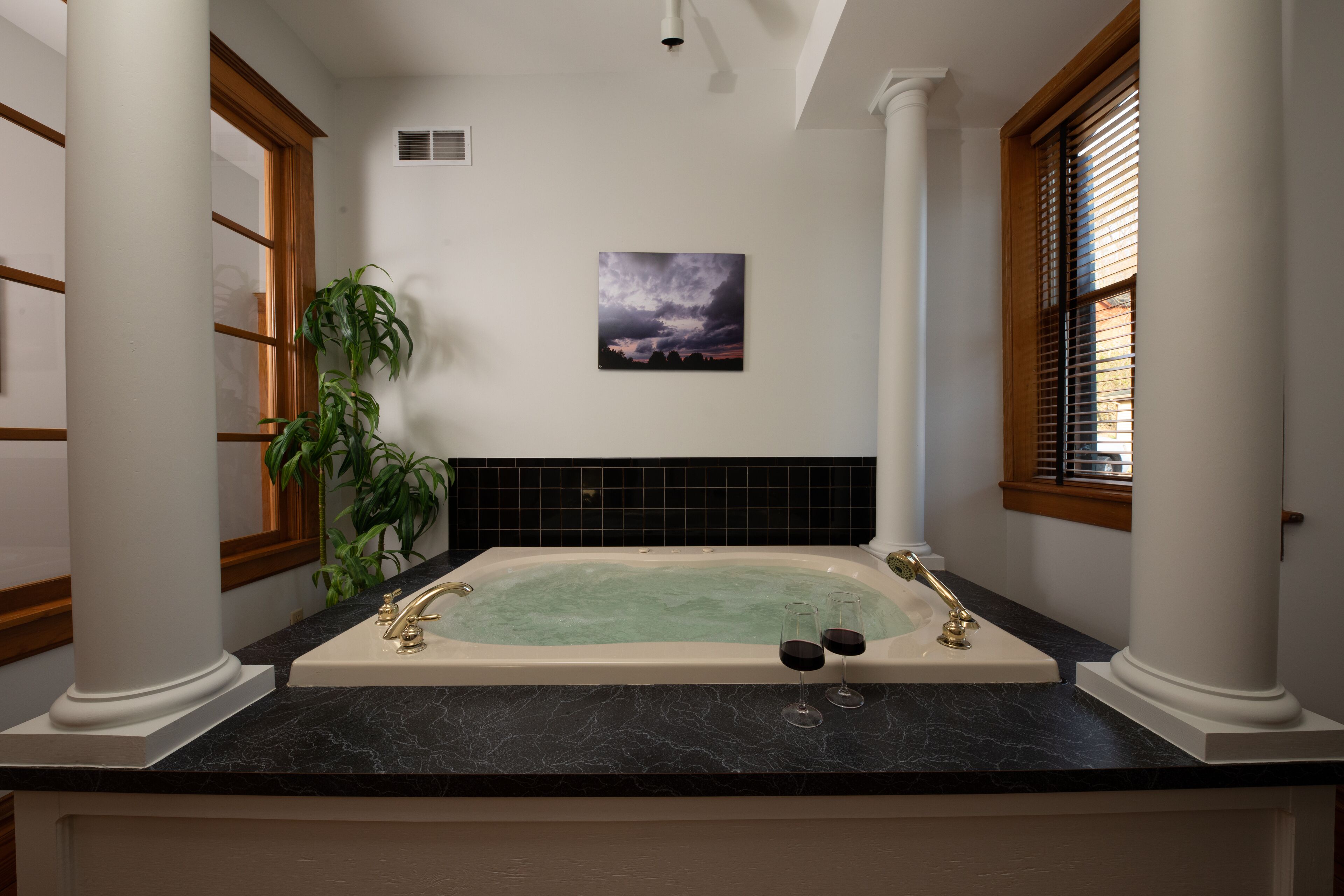Ein Badezimmer mit einer freistehenden Badewanne, einem Blumentopf und einem gerahmten Bild an der Wand.