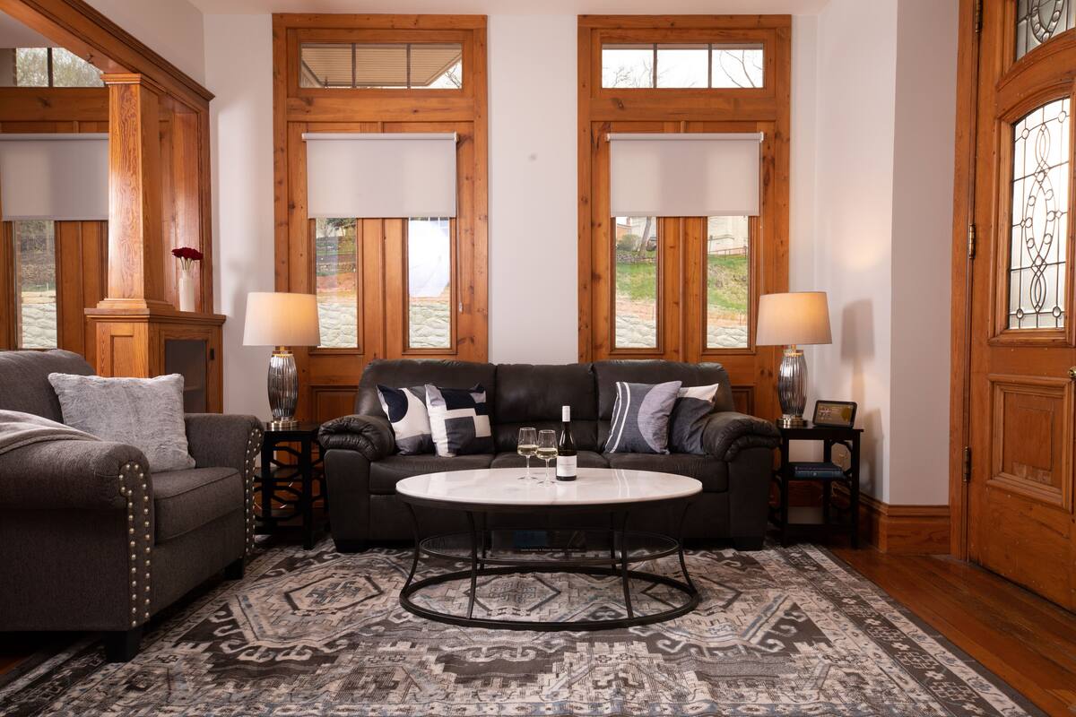 A living room with a dark brown leather sofa, two side chairs, a round coffee table, and a patterned rug.