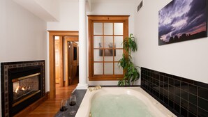 A bathroom with a bathtub, a fireplace, and a large window. - Hotel Galena (Galena)