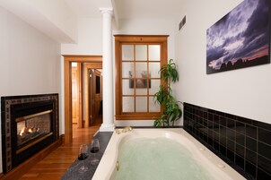 A bathroom with a bathtub, a fireplace, and a large window.