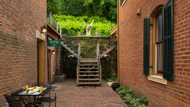 A brick building with a staircase leading to a balcony, a breakfast table with chairs, and a sign indicating a breakfast room office. - Hotel Galena (Galena)