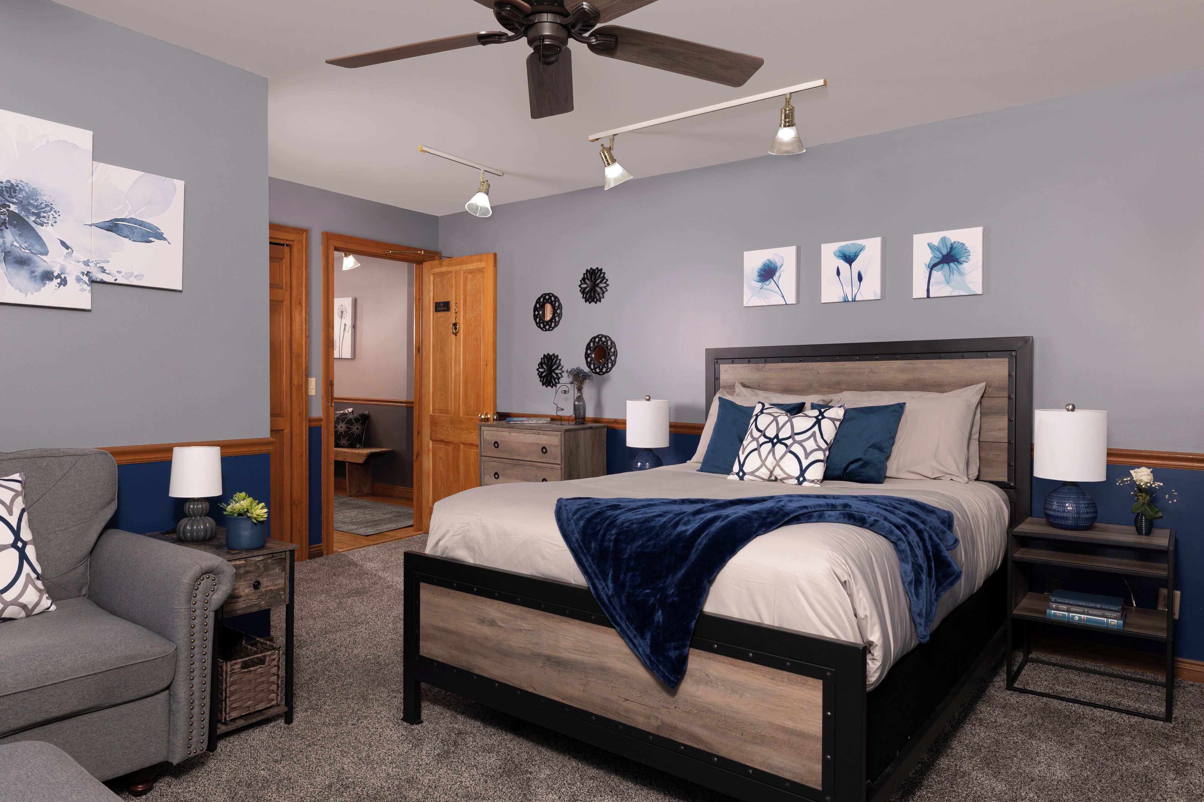 A bedroom with a bed, bedside tables, a chair, and a ceiling fan.