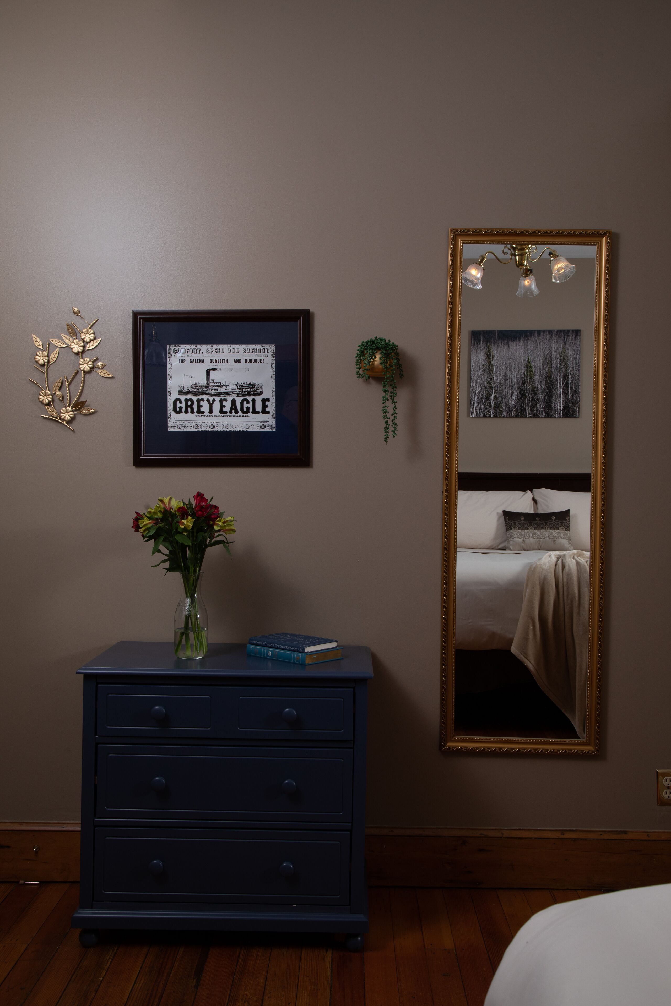 A bedroom with a bed, a dresser, a mirror, and a framed picture on the wall.