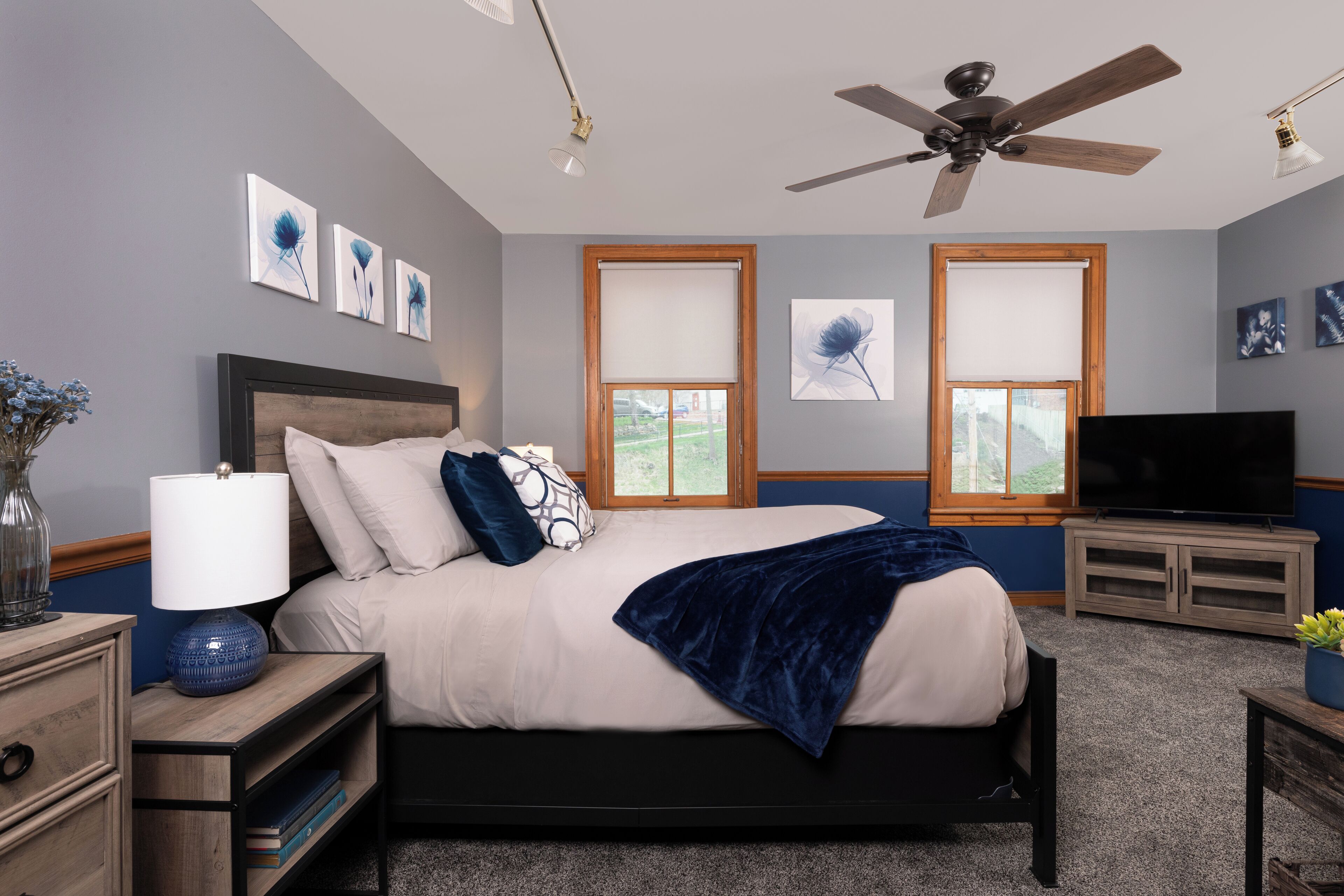 Ein Schlafzimmer mit einem Bett, einem Fernseher, einem Deckenventilator und Kunstwerken an den Wänden.