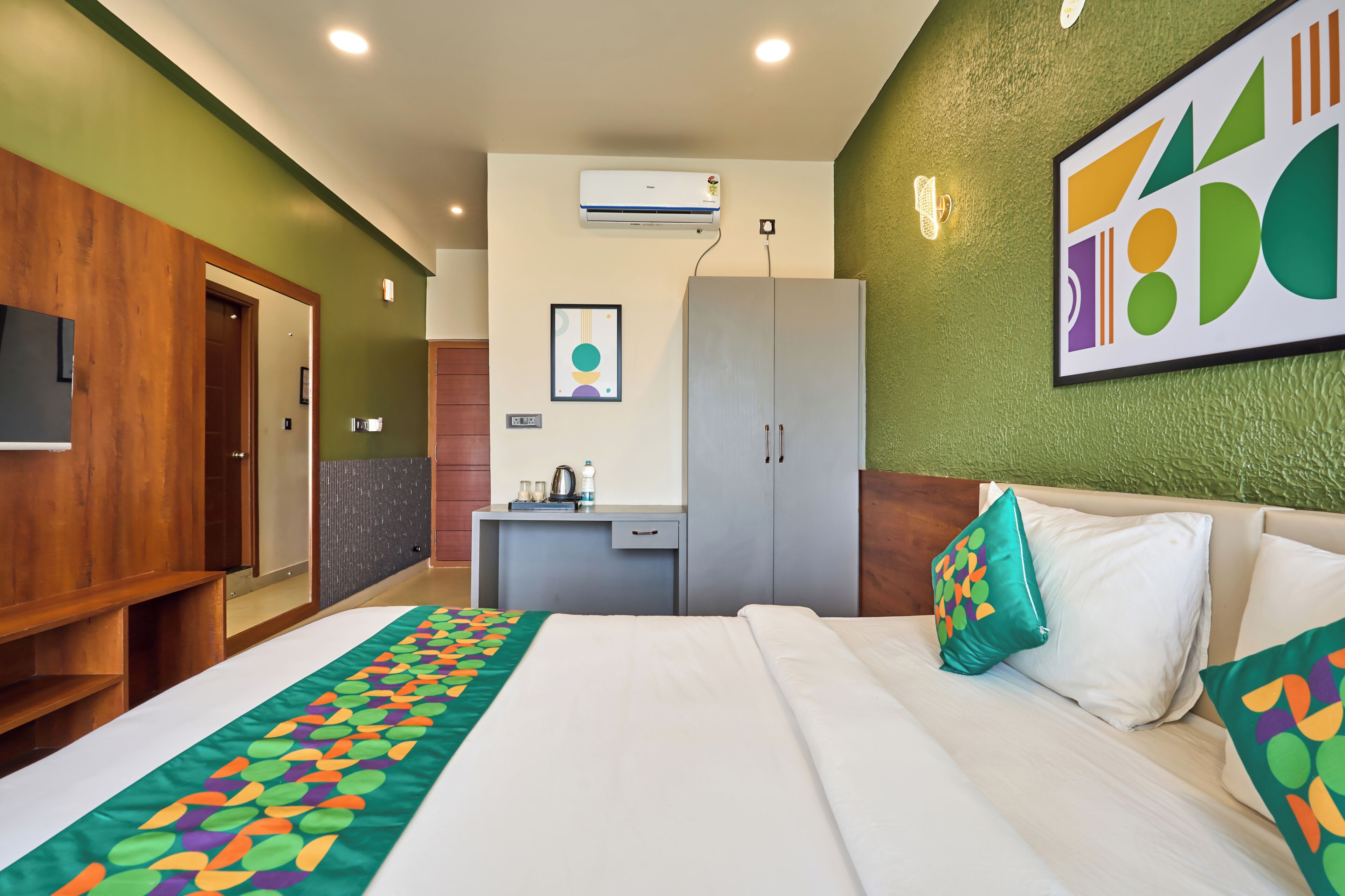 Habitación de hotel con cama, escritorio, armario y aire acondicionado de pared.