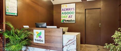 Una recepción con el letrero 'treebo', una planta en maceta y un cartel que dice 'Siempre es un buen día en treebo'.