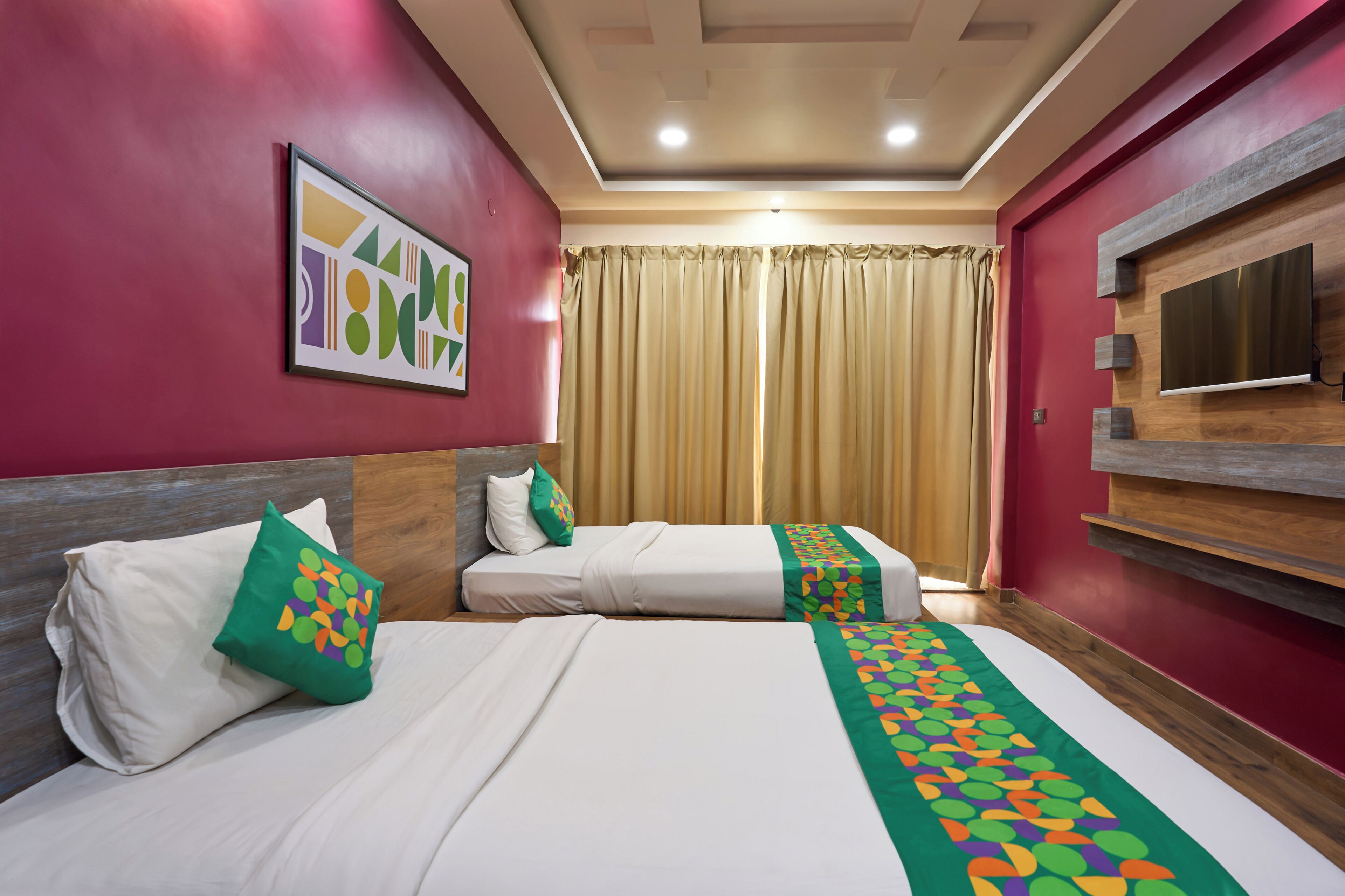 Quarto de hotel com duas camas, televisão, pintura e janela com cortinas.