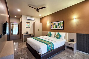 A hotel room with a bed, bedside table, nightstand, and a ceiling fan. - Treebo Sky Vista Suites with Hill View (Chikkamagaluru)
