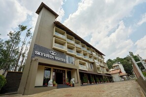 A multi-story hotel named 'Skyvista Suites' with balconies, a stone-paved entrance, and potted plants. - Treebo Sky Vista Suites with Hill View (Chikkamagaluru)