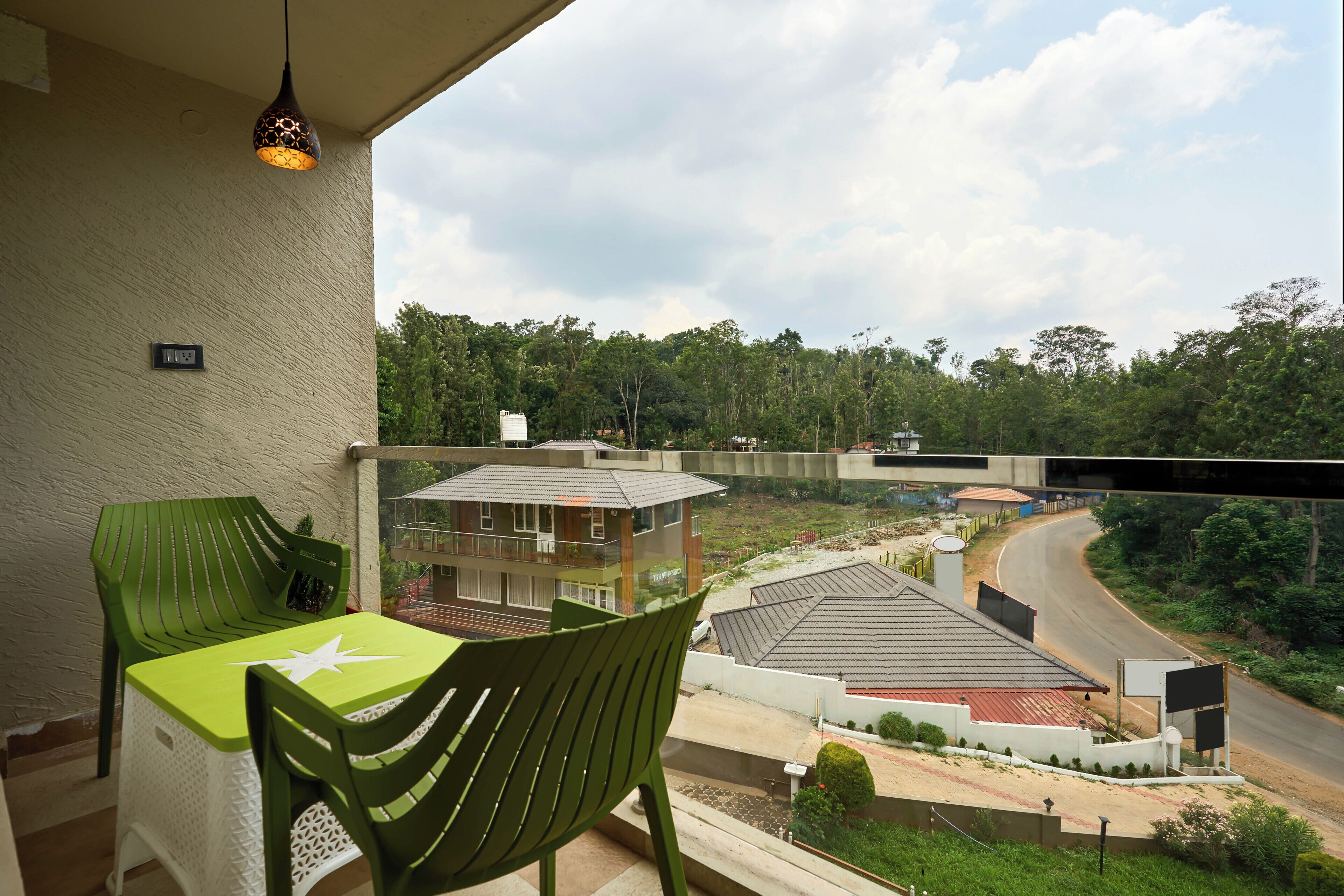 Varanda com mesa e cadeiras, com vista para a rua e edifícios.