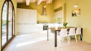 A modern kitchen with white cabinets, a dining table with chairs, and a large window. - Two-story Luxury in Siena Resort at Sage (Trequanda)