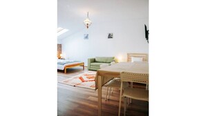 Et rummeligt værelse med en seng, en grøn sofa, et spisebord og en lysekrone.