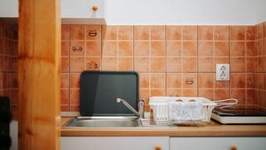 Et køkken med vask, sort skærebræt og hvid opvaskestativ.