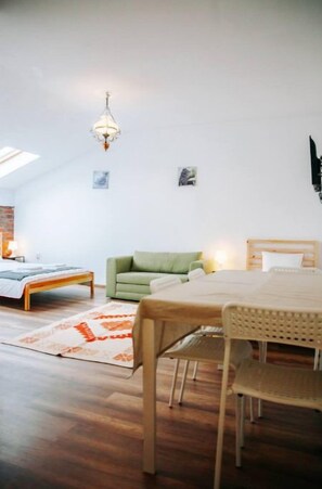 A spacious room with a bed, a green sofa, a dining table, and a chandelier. - Kali Host Apartman 1 (Târgu Mureș)