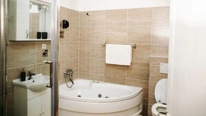 Et moderne badeværelse med en glasbrusekabine, et fristående badekar og et toilet.