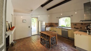 A kitchen with a wooden table, a refrigerator, a dishwasher, and a window providing natural light.