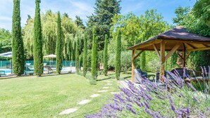 Un jardin agrémenté d’un belvédère, d’une piscine et de grands arbres.
