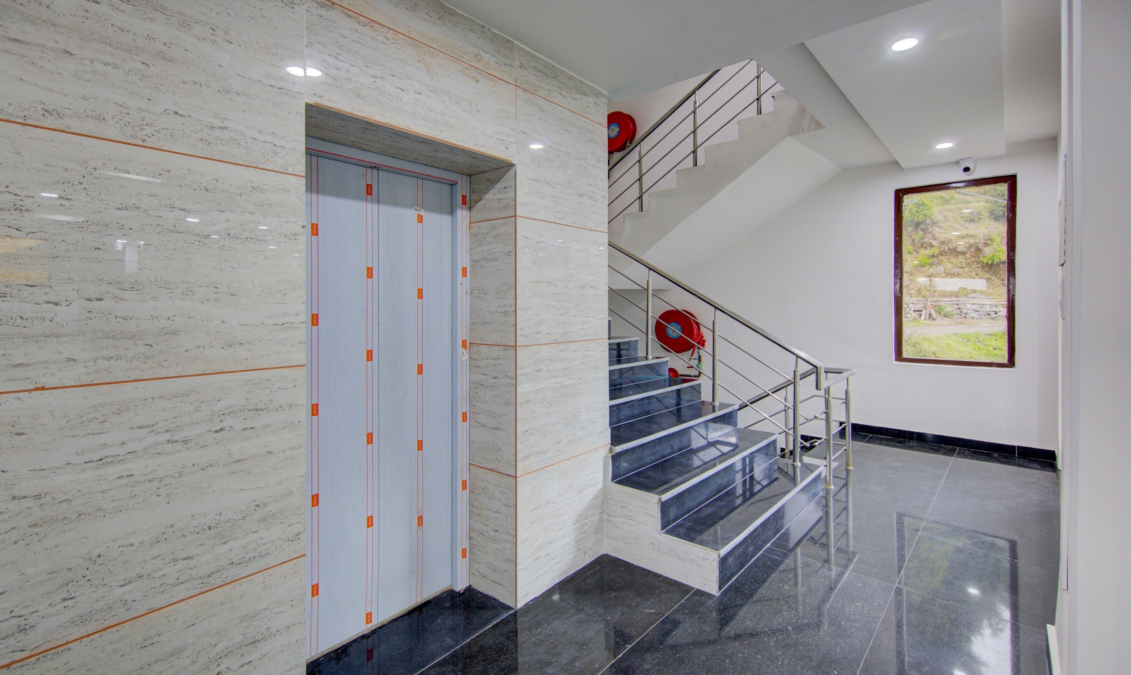 Um interior moderno com parede de mármore, escada com grades de metal e um quadro na parede.