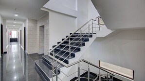Un interior moderno con una escalera, pisos pulidos y un pasillo que conduce a una puerta con un extintor.