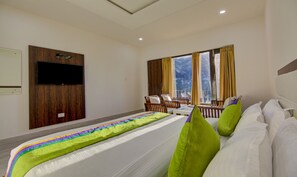 A hotel room with a bed, a TV mounted on the wall, a window with curtains, and a view of the outside. - Treebo Down Town, Dalhousie (Dalhousie)