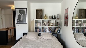 Un dormitorio con cama, estantería, escritorio y espejo.