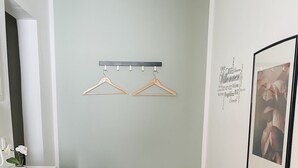 Ett rum med en bänk, en hängande klädställning, en inramad tavla och en vävd matta.