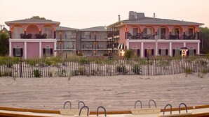 Un hotel frente a la playa con varios balcones y una playa de arena.