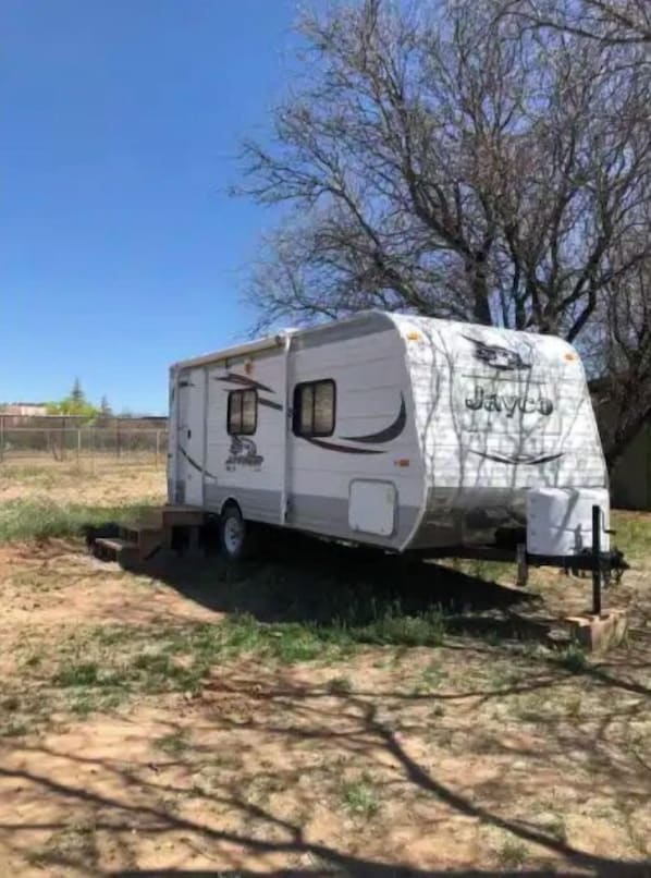 A Jayco RV parked in a grassy area with a fence in the background.