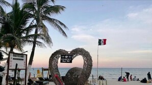 A beach with a heart-shaped structure, a flag, and a signboard. - MAYAB Playa - 5Th. Ave (Playa del Carmen)